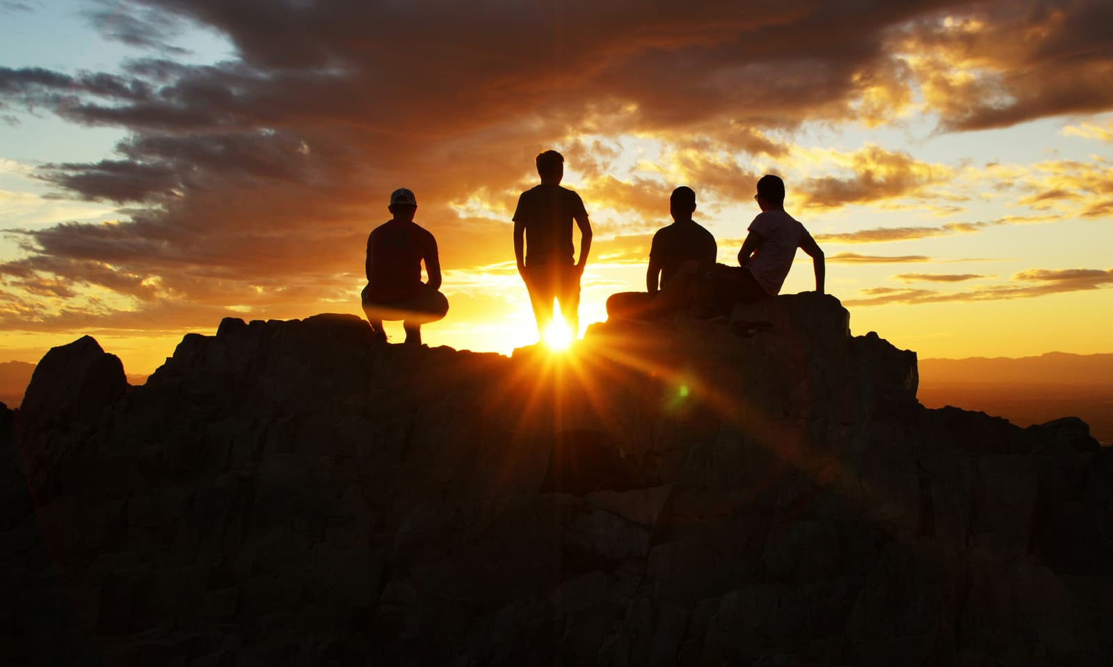 Four friends silhouetted on Piestewa Peak at sunset